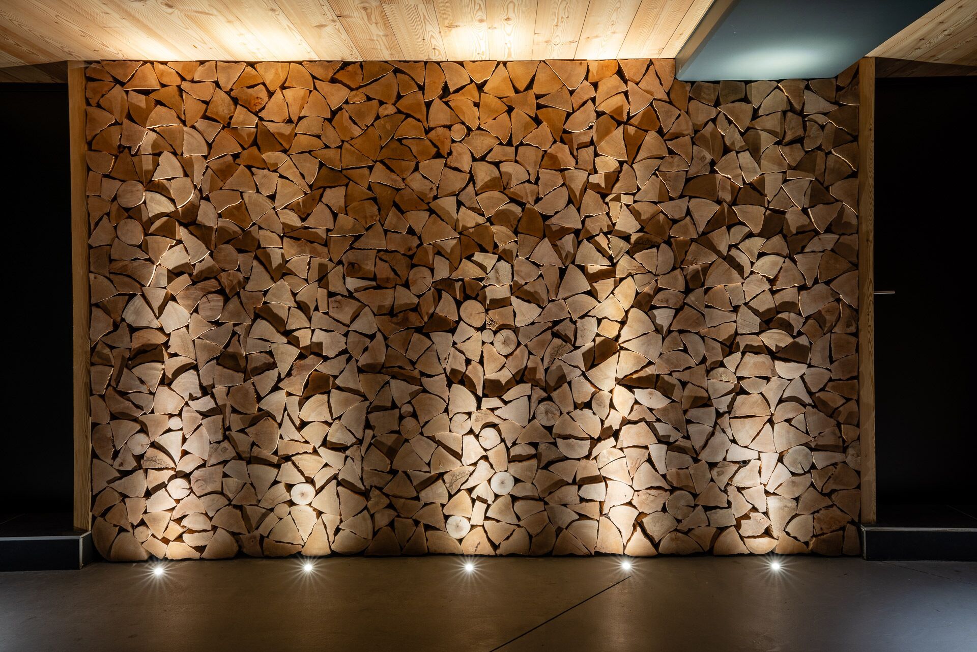 A wall made of stacked logs with a wooden ceiling and a concrete floor.