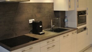 A modern kitchen with a built-in stove, a coffee maker, a sink, and cabinets. - Superb modern apartment Panoramic sea view - Private garage (Nice)