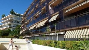 A modern multi-story hotel with balconies, a swimming pool, and a landscaped garden. - Superb modern apartment Panoramic sea view - Private garage (Nice)