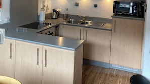 Een kleine keuken met een roestvrijstalen fornuis, een magnetron en houten keukenkastjes.
