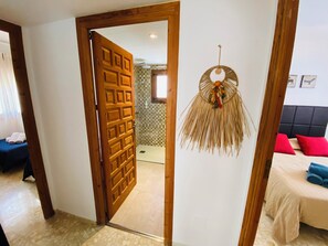 Een hotelkamer met een houten deur, een bed met rode en blauwe kussens en een wanddecoratie.