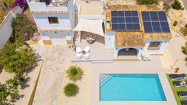 Een moderne villa met een zwembad, zonnepanelen en een terras.