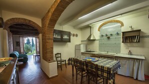 Une cuisine spacieuse avec un coin repas, dotée d’un parquet à motifs en chevrons, de chaises en bois et d’un îlot central.