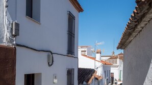A narrow street with white buildings, a tiled roof, and a clear blue sky.