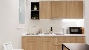 A modern kitchen with wooden cabinets, a built-in microwave, and a sink. - Chic and Cosy Flat in Plaka (Athina)