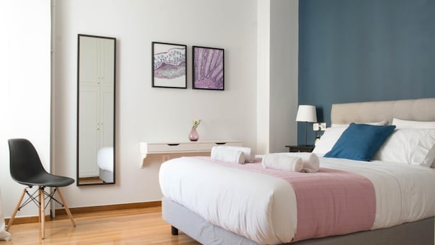 A modern bedroom with a bed, bedside table, lamp, and a chair. - Chic and Cosy Flat in Plaka (Athina)