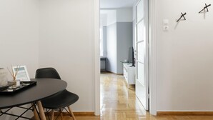 A modern, minimalist room with a dining table and chairs, a flat-screen TV, and a wooden floor. - Chic and Cosy Flat in Plaka (Athina)