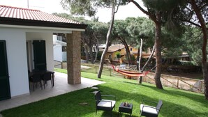A patio with two chairs and a small table, a hammock, and a view of a house with a tiled roof. - ROSA DEI VENTI - SAN PIETRO A MARE (San Pietro a Mare)