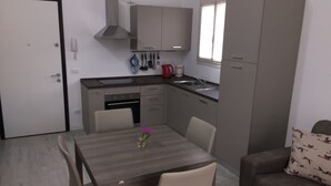 A compact kitchen with a dining area, a sofa, and a door. - ROSA DEI VENTI - SAN PIETRO A MARE (San Pietro a Mare)