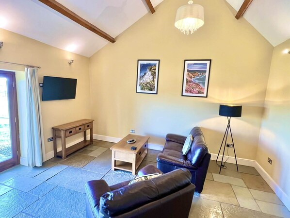 A living room with a sofa, a coffee table, a TV mounted on the wall, and a floor lamp.