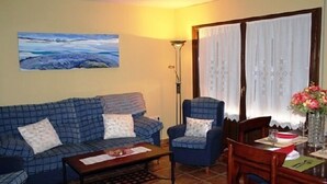Un salón con sofá, sillón y mesa de comedor con sillas.