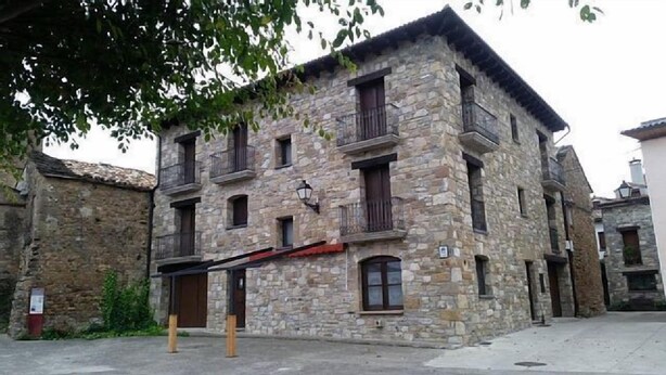 Un edificio de piedra con múltiples ventanas y balcones, que presenta un estilo arquitectónico tradicional.