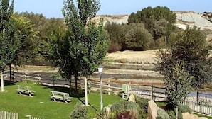 Un parque con bancos, un sendero pavimentado y una zona rocosa con árboles.