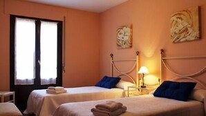 Habitación de hotel con dos camas, una mesita de noche con lámpara y obras de arte en las paredes.