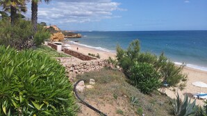 A beach with a stone wall, palm trees, and a clear view of the ocean. - NEWLY REFRUB LUX 2 bed Apart (Sleeps 4) FREE Wi-Fi  Close to Marina Beach & Golf (Vilamoura)