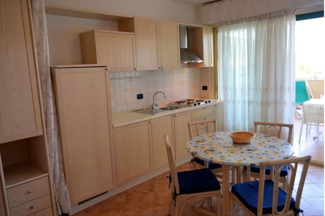 A compact kitchen with wooden cabinets, a gas stove, and a dining table with chairs.