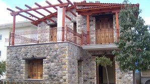 A stone building with a wooden balcony and a wooden fence in front.