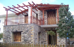 A stone building with a wooden balcony and a wooden fence in front.