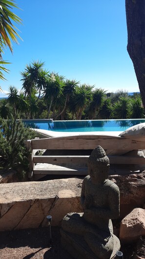 Une statue de pierre dans un jardin, avec une piscine et des palmiers en arrière-plan.