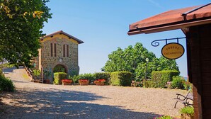 Un chemin de gravier mène à un bâtiment en pierre sur lequel est apposée une enseigne indiquant « PODERE CASAROTTA ».
