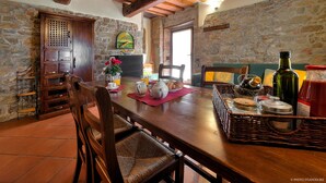 Un coin repas rustique avec une table en bois, des chaises et un mur en pierre en arrière-plan.