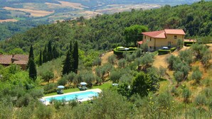 Une villa avec piscine, entourée de verdure et de collines.
