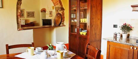 A dining area with a wooden table set for tea, a cabinet with glass doors, and a mirror above the table.