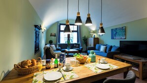 A cozy living room with a dining table set for breakfast, a sofa, and a TV. - Vacation in the Harz Mountains the special ****Holiday apartments Burggraf im Zwinger Goslar (Goslar)