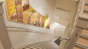 A staircase with a historical timeline poster on the wall, a handrail, and a wooden floor. - Vacation in the Harz Mountains the special ****Holiday apartments Burggraf im Zwinger Goslar (Goslar)