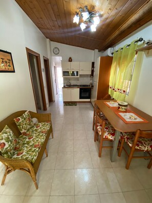 Een koelkast, een oven, een kookplaat, kookgerei, borden en bestek