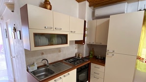 A compact kitchen with white cabinets, a sink, a stove, and a refrigerator.