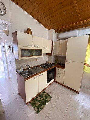 Een koelkast, een oven, een kookplaat, kookgerei, borden en bestek