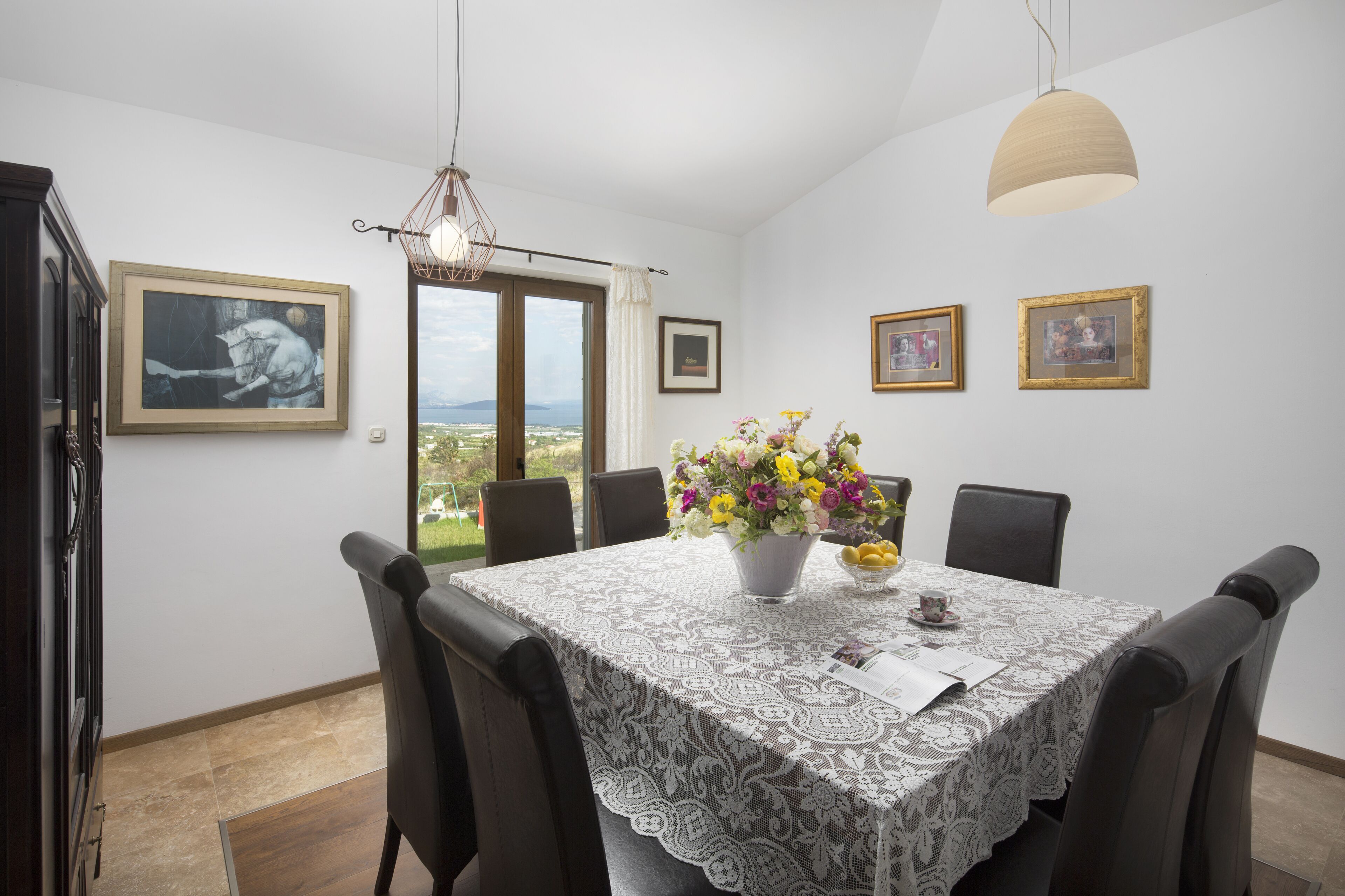 Un coin repas avec une table dressée pour quatre personnes, un vase de fleurs et des tableaux encadrés accrochés au mur.