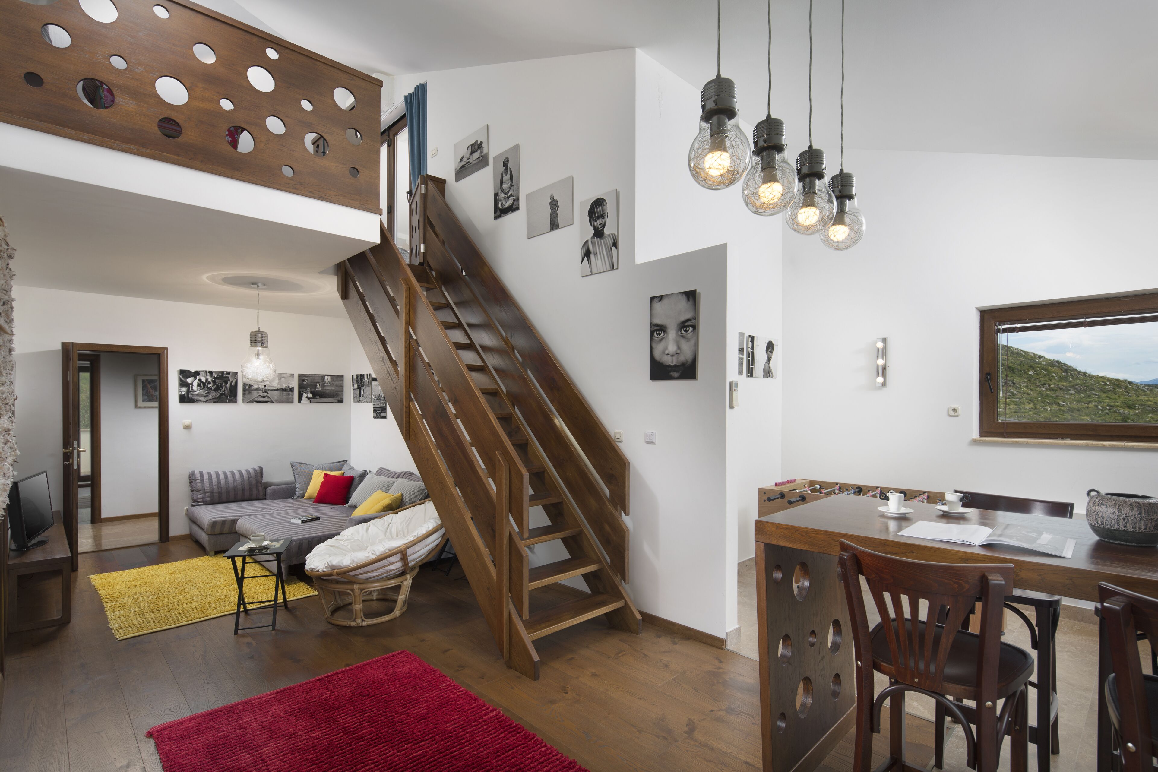 Ein modernes Interieur mit einer Holztreppe, einem Essbereich und einem Wohnzimmer mit einer Couch und Kissen.