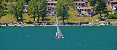 A sailboat on a calm lake with houses in the background.