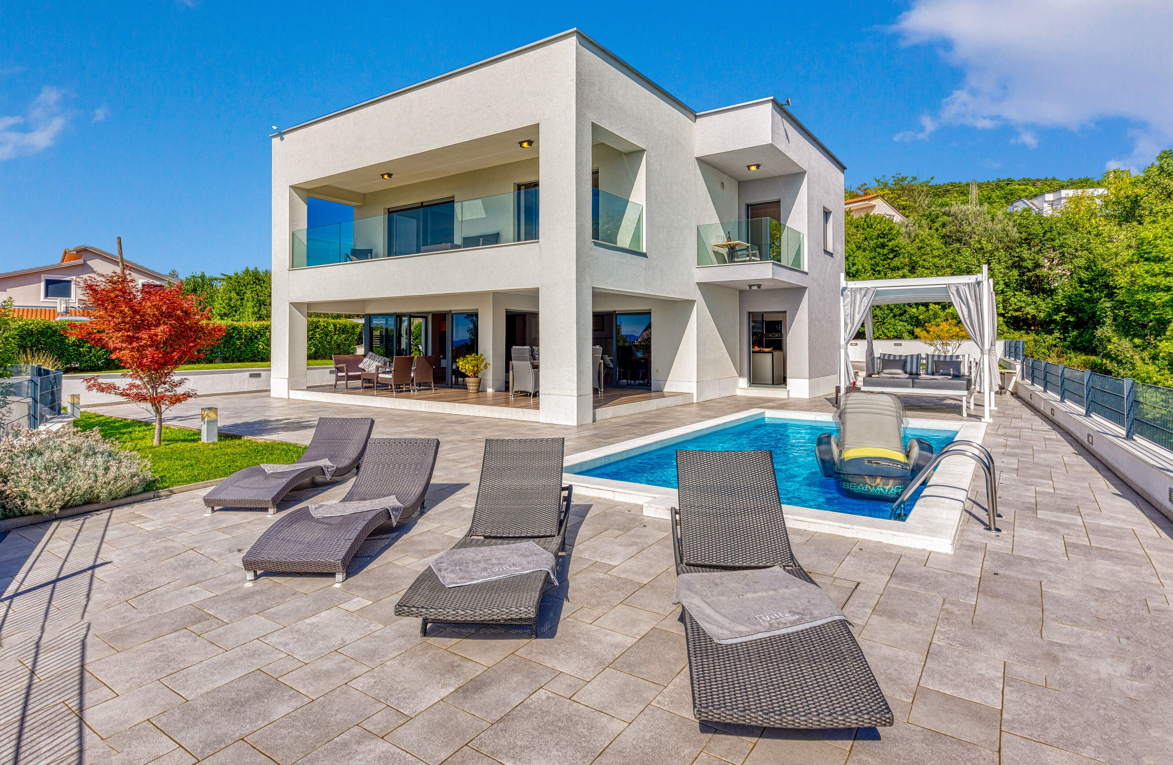 Una moderna casa a due piani con piscina, area salotto esterna e portico coperto.