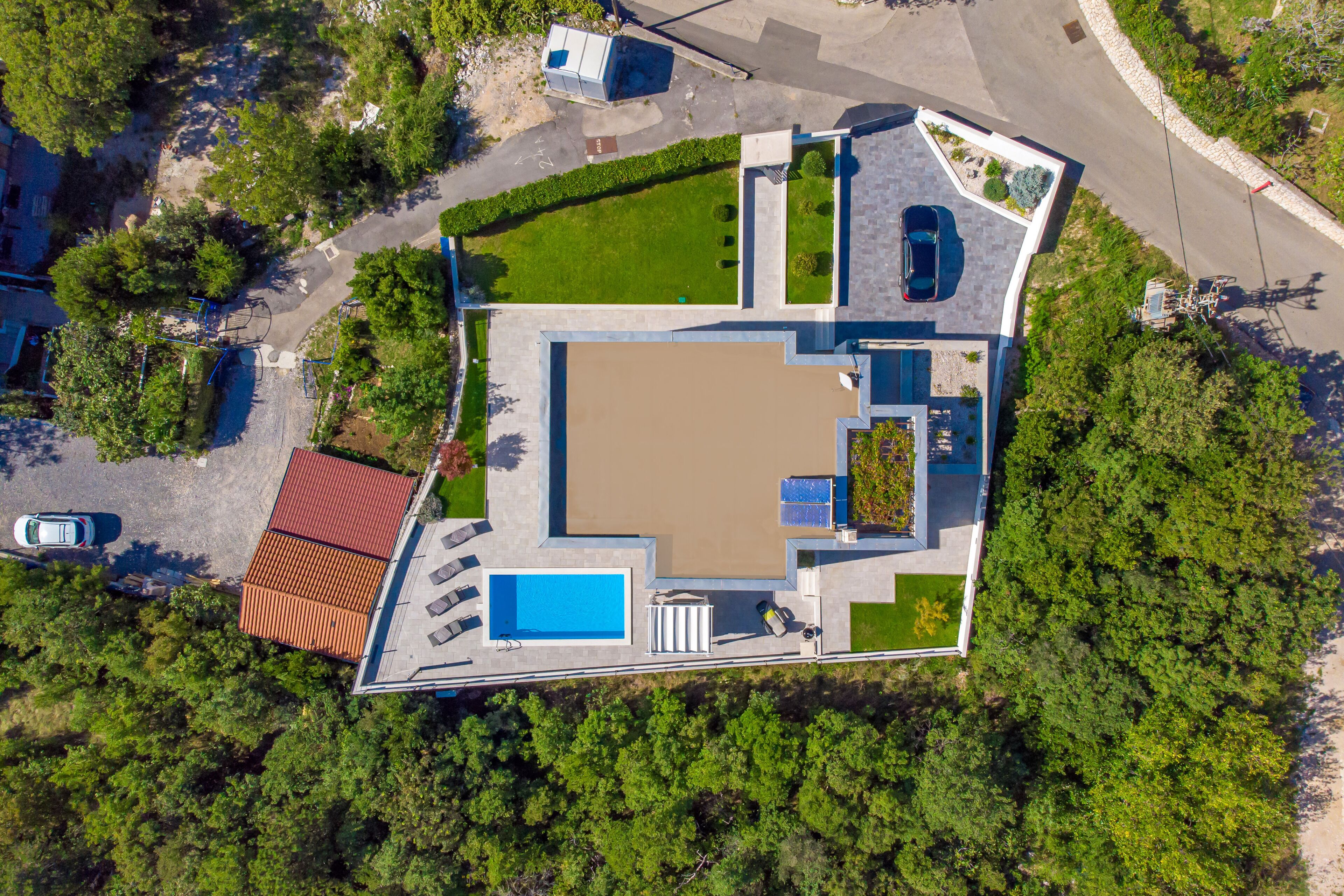 Vista aèria d'una casa moderna amb un ampli pati central, una piscina i una zona d'estar coberta a l'aire lliure.