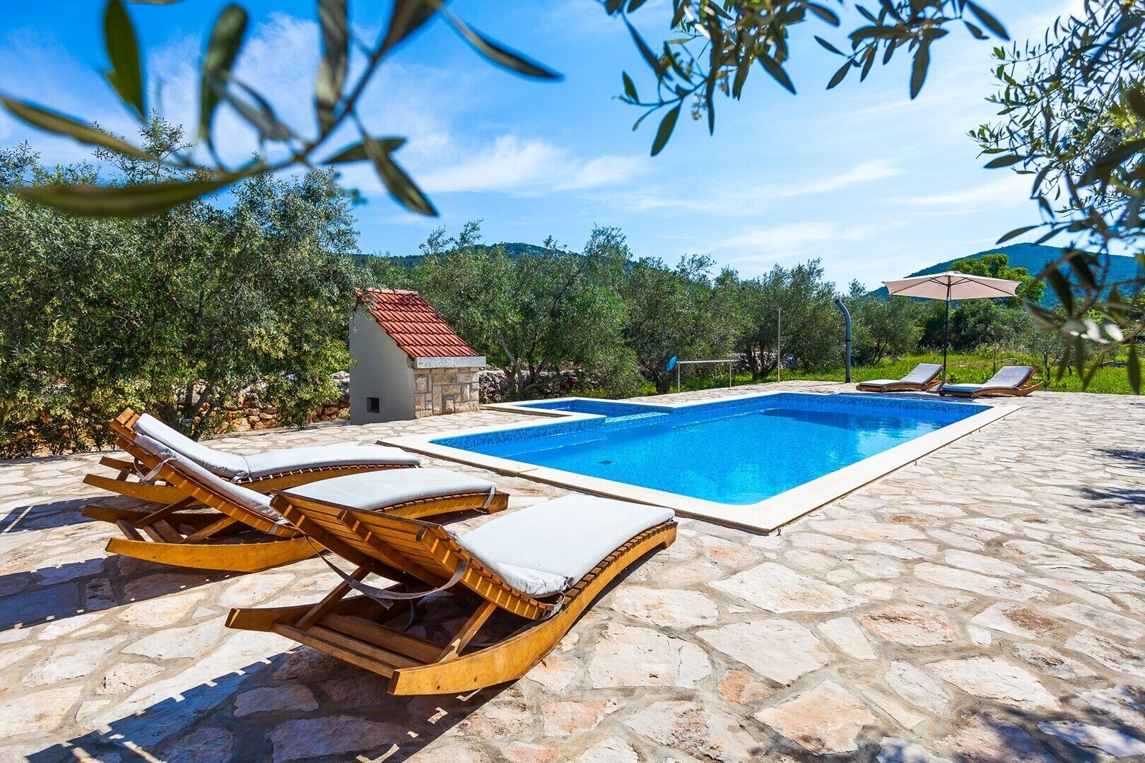En swimmingpool med liggestole og en flisebelagt terrasse.