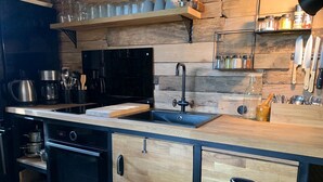 A modern kitchen with wooden cabinetry, a black countertop, a built-in oven, a sink, and various kitchen utensils and appliances.