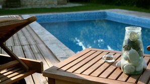 A wooden deck with a pool table and a glass bottle with stones.