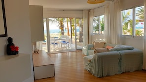 Ein Zimmer mit einer Couch, einem Tisch und Blick auf den Strand.