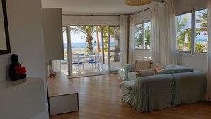 Une chambre moderne avec vue sur la plage, comprenant un canapé, une table à manger et une statue.
