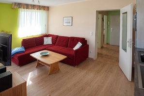 A living room with a red sofa, a wooden coffee table, and a television.