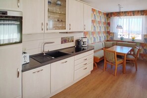 A compact kitchen with a sink, a coffee maker, and a dining area with a table and chairs. - Cozy vacation apartment in Ahlbeck with sea view and balcony on Usedom (Ahlbeck)