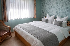 A bedroom with a bed, pillows, a chair, and a window with curtains. - Cozy vacation apartment in Ahlbeck with sea view and balcony on Usedom (Ahlbeck)