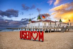 A beach with a large red sign reading 'USEDOM' and a building with multiple flags.