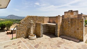 A stone-built outdoor kitchen area with a stone wall and a view of the countryside. - Holiday feeling in a quiet area apartment on olive grove with Wi-Fi! (Gonnesa)