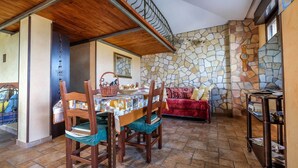 A dining area with a stone wall, wooden ceiling, and a red sofa. - Holiday feeling in a quiet area apartment on olive grove with Wi-Fi! (Gonnesa)