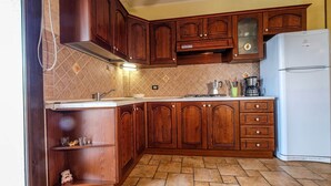 A kitchen with wooden cabinets, a sink, a stove, and a refrigerator. - Holiday feeling in a quiet area apartment on olive grove with Wi-Fi! (Gonnesa)
