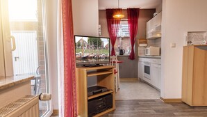 Eine kleine Küche mit Fernseher, Holzschrank und Blick auf Boote durch das Fenster.